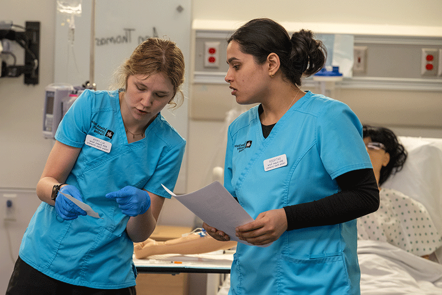 Two nursing students, wearing their ISU scrubs, gain knowledge and skills in one of the Nursing Learning Resource Center skill labs at Indiana State University.