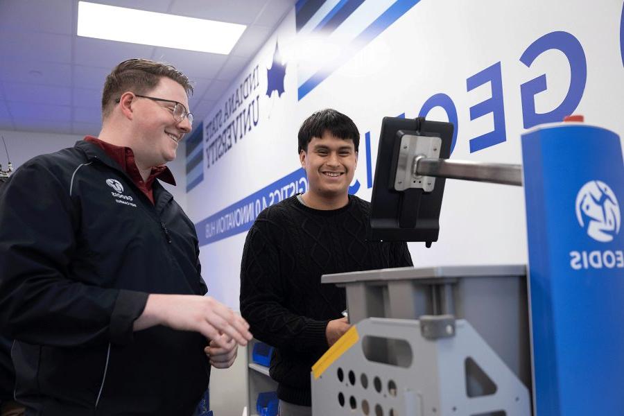 Two individuals work with a machine in the Geodis Logisitics 4.0 Innovation Hub