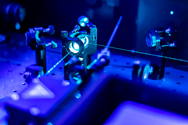 Physics optical lab equipment with light sources in a blue-tinted photo.